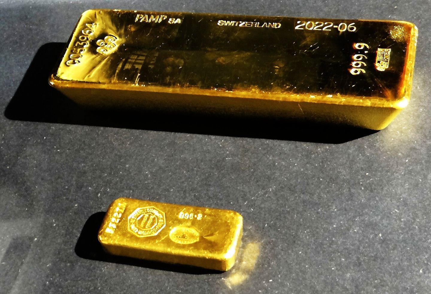 A stamped one-kilogram gold bar and a smaller cast ingot.