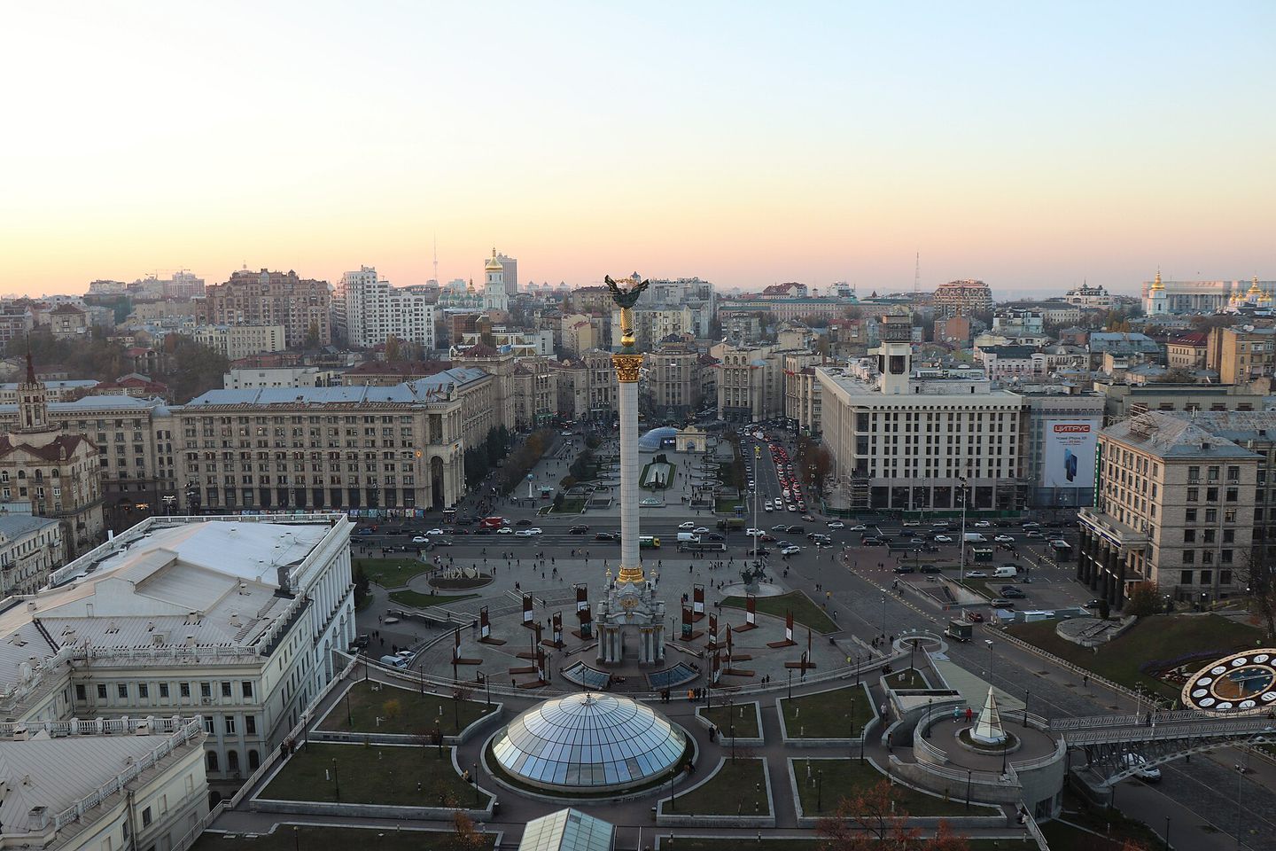 La place de l'Indépendance, au centre de Kyiv, au crépuscule, vue d'en haut : la colonne du monument de l'Indépendance au milieu, la circulation sur le Khrechtchatyk, et la ville jusqu'à l'horizon